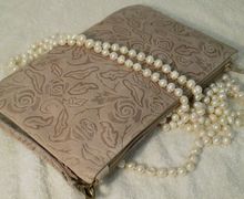 A beige leather clutch with floral design