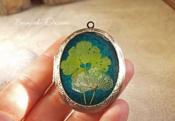A locket with clover and hydrangea on an emerald background